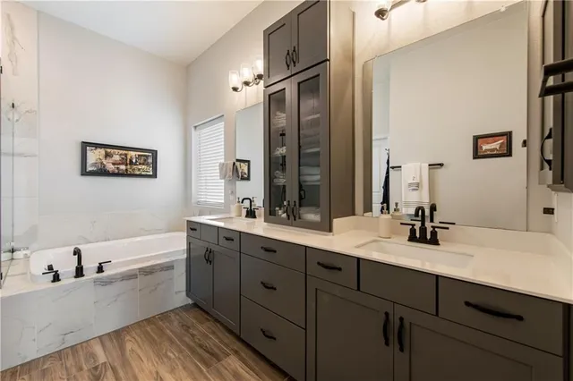 a bathroom with a double vanity sink a mirror a bathtub and