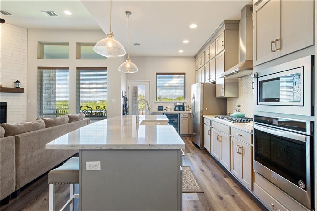 7117 Jument Drive Austin, TX 78738 - Photo 40 of 40 Kitchen with stainless steel appliances, a kitchen island, open floor plan, wall chimney exhaust hood, and wood finished floors