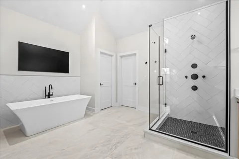 a bathroom with a tub a mirror and a shower