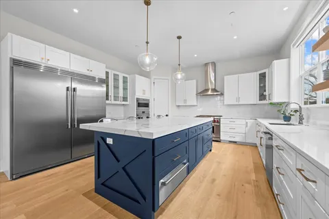 a large kitchen with a center island wooden floor stainless steel appliances and a window