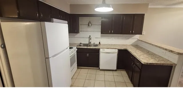 a kitchen with granite countertop a refrigerator and a sink