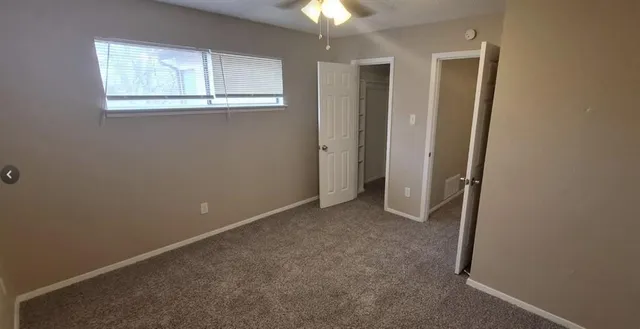 an empty room with windows and chandelier fan