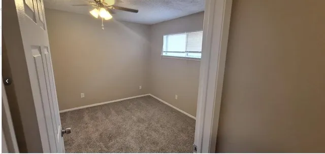 an empty room with windows and chandelier fan
