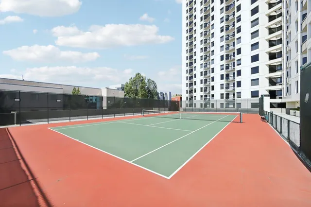 a view of a tennis ground with large trees