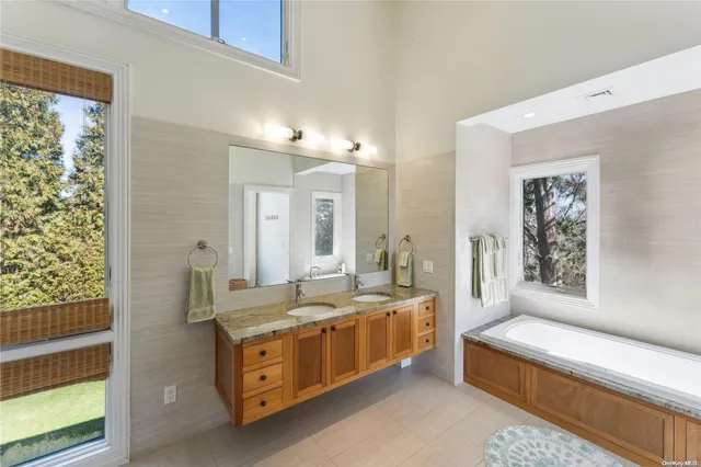 a spacious en suite bathroom with a double vanity sink a large mirror and a bathtub