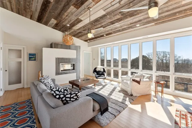 a living room with furniture large windows and wooden floor