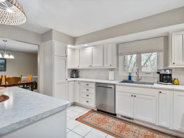 a kitchen with white cabinets a sink dishwasher and a stove with wooden floor
