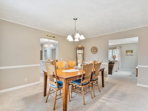 a dining room with wooden floor a chandelier a wooden table and chairs