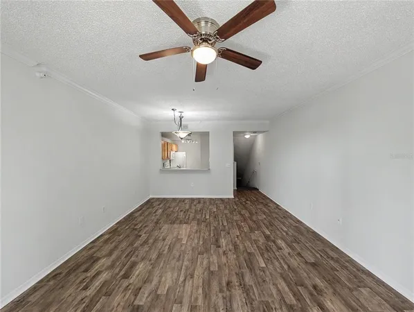 an empty room with wooden floor ceiling fan and windows