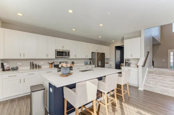a kitchen with stainless steel appliances kitchen island granite countertop a sink a stove a dining table and chairs