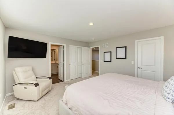 a bedroom with a large bed a flat tv screen and white walls