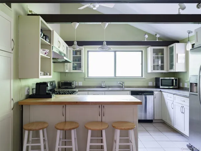 a kitchen with stainless steel appliances a sink a stove a table and chairs