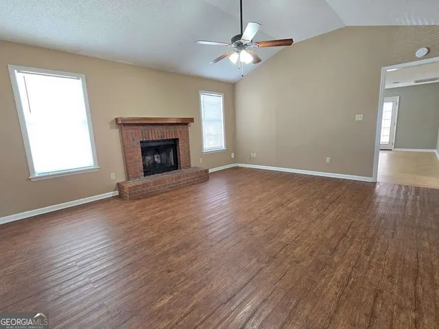 an empty room with wooden floor fireplace and window