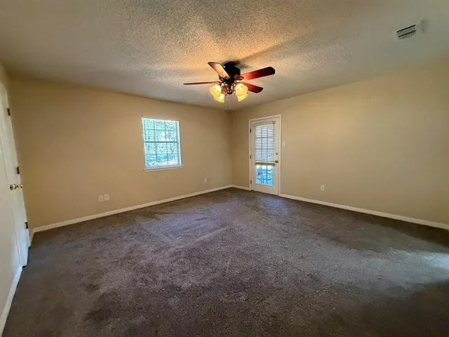 an empty room with windows and fan