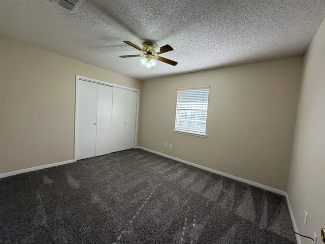 an empty room with windows and fan