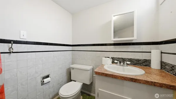 a bathroom with a granite countertop sink vanity mirror and toilet