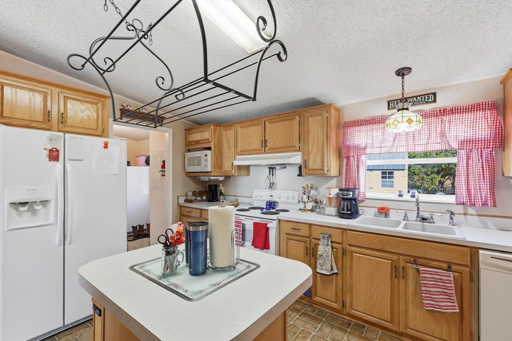 609 Cedar Mills Road Gordonville, TX 76245 - Photo 15 of 38 a kitchen with a refrigerator a sink dishwasher a stove and a dining table with wooden floor