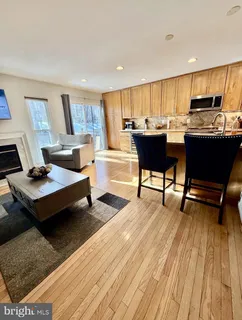a living room with a couch dining table wooden floor and a view of kitchen