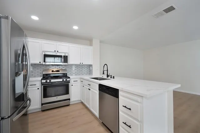 a kitchen with stainless steel appliances granite countertop a sink stove oven and refrigerator