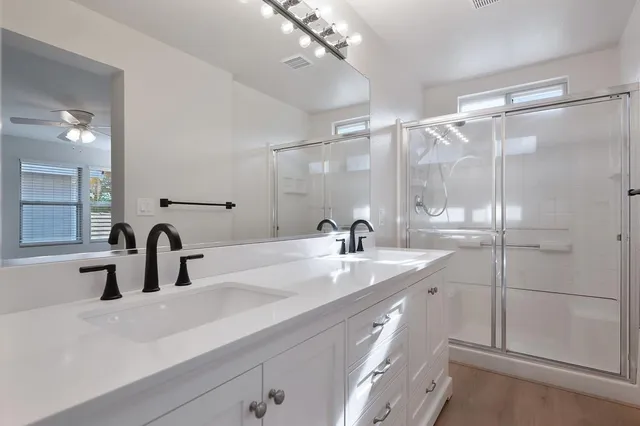 a bathroom with a double vanity sink mirror and shower