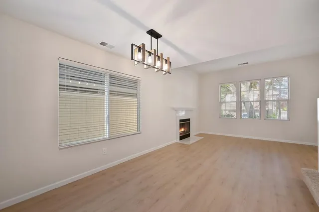 an empty room with windows and chandelier fan