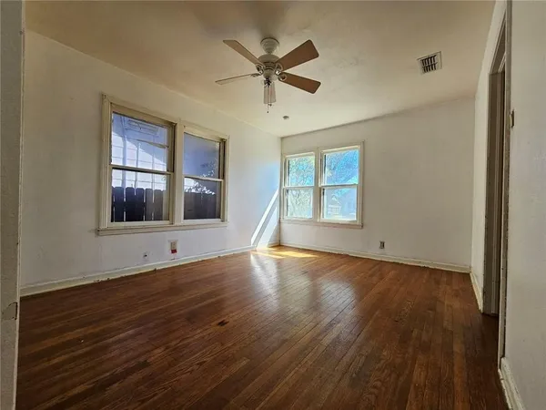 a view of an empty room with wooden floor and a window