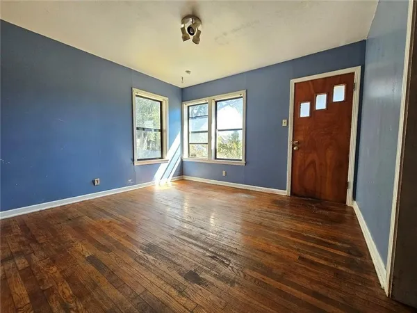 a view of an empty room with wooden floor and a window