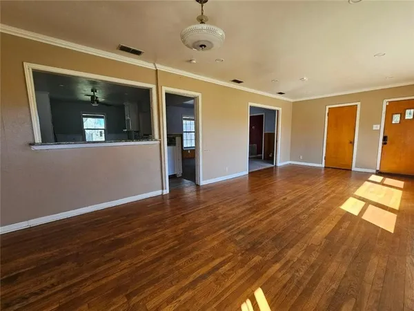 a view of an empty room with wooden floor and a window