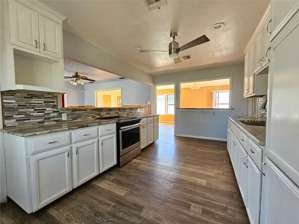 a large kitchen with cabinets wooden floor and stainless steel appliances