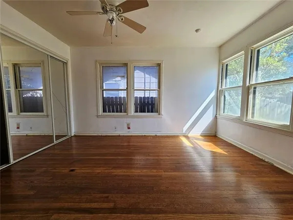 a view of an empty room with a window and wooden floor