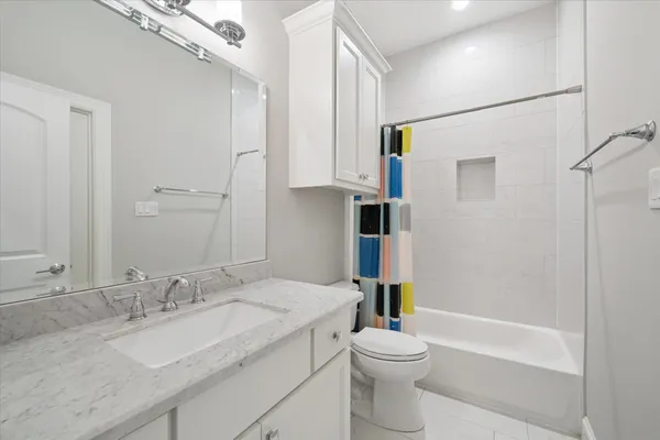 a bathroom with a granite countertop sink toilet mirror and bathtub