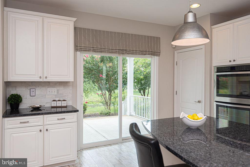 30134 Islander Beach Road Frankford, DE 19945 - Photo 17 of 73 a kitchen with a stove a refrigerator a sink a dining table and chairs with wooden floor