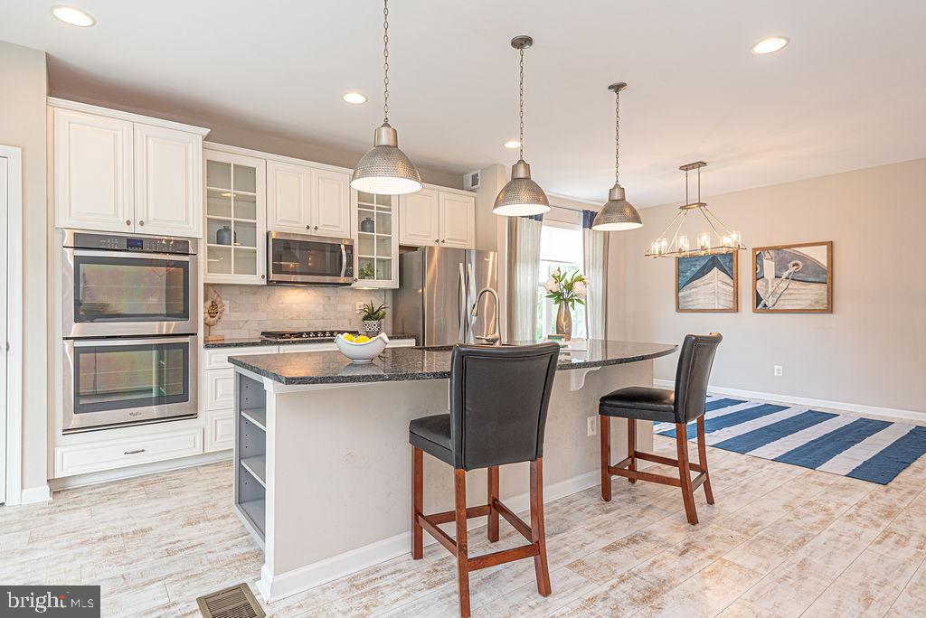30134 Islander Beach Road Frankford, DE 19945 - Photo 21 of 73 a kitchen with stainless steel appliances granite countertop a stove a sink a microwave a refrigerator a island with wooden floor and cabinets