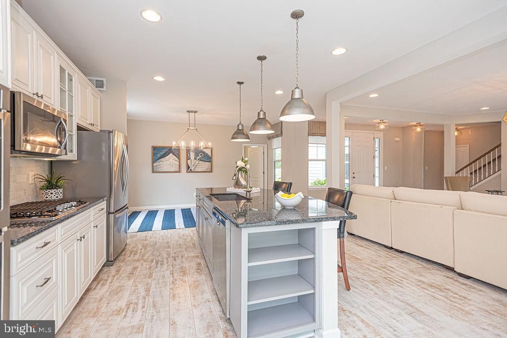 30134 Islander Beach Road Frankford, DE 19945 - Photo 22 of 73 a kitchen with stainless steel appliances kitchen island granite countertop a stove a sink a refrigerator and white cabinets with wooden floor