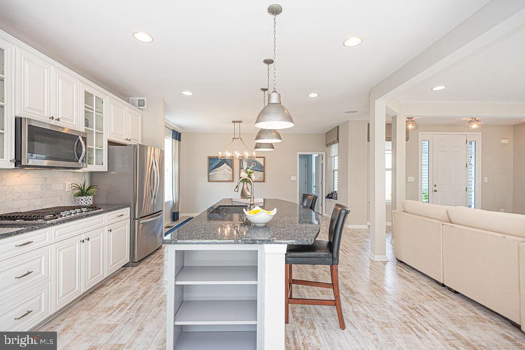 30134 Islander Beach Road Frankford, DE 19945 - Photo 58 of 73 a kitchen with granite countertop a stove a sink a refrigerator and a dining table with wooden floor
