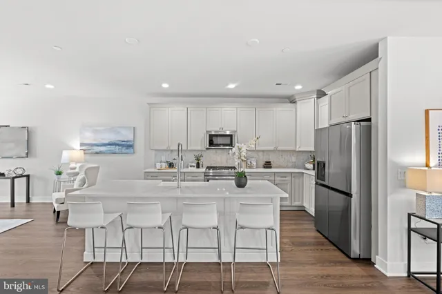 a kitchen with stainless steel appliances granite countertop a stove a sink a refrigerator and white cabinets with wooden floor