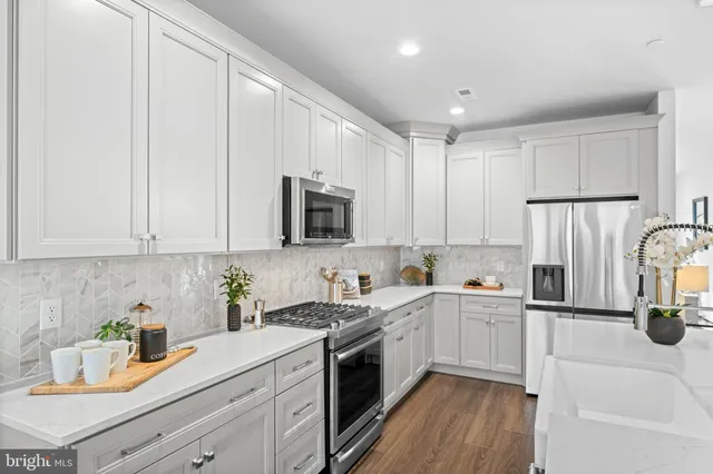a kitchen with a sink white cabinets and white appliances