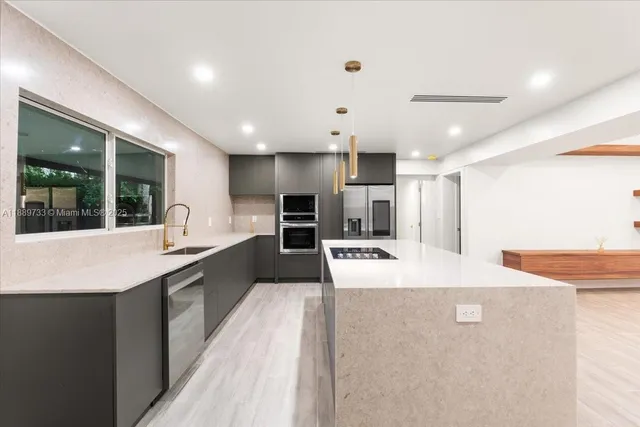 a large kitchen with kitchen island a sink a counter top space wooden floor and a large window