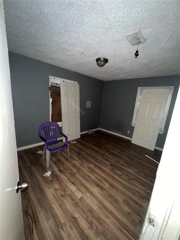 4224 Ramey Avenue Fort Worth, TX 76105 - Photo 12 of 19 Unfurnished room featuring dark wood-style floors and a textured ceiling