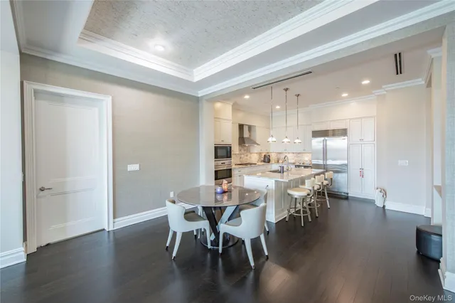 a kitchen with stainless steel appliances granite countertop a stove top oven a refrigerator and white cabinets with wooden floors