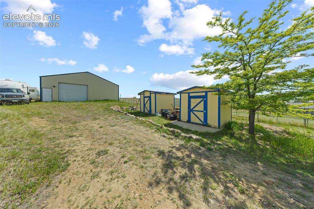 13075 Blaney Road South Peyton, CO 80831 - Photo 30 of 40 Metal-sided barn featuring large pull-through garage doors and personnel door. Two permanent 10x12 storage sheds also included.