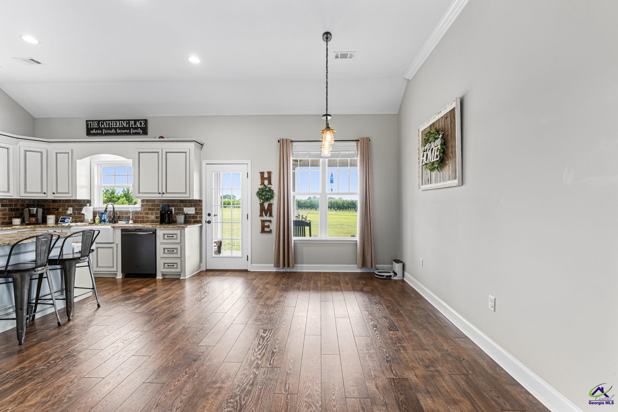 180 Woodland Trail Road Cochran, GA 31014 - Photo 7 of 25 a kitchen with stainless steel appliances granite countertop a stove top oven a refrigerator a sink dishwasher and a dining table with wooden floor
