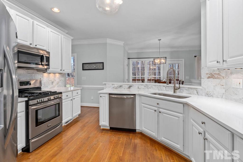 10400 Old Warden Road Raleigh, NC 27615 - Photo 12 of 30 a kitchen with stainless steel appliances granite countertop a sink cabinets and a wooden floor