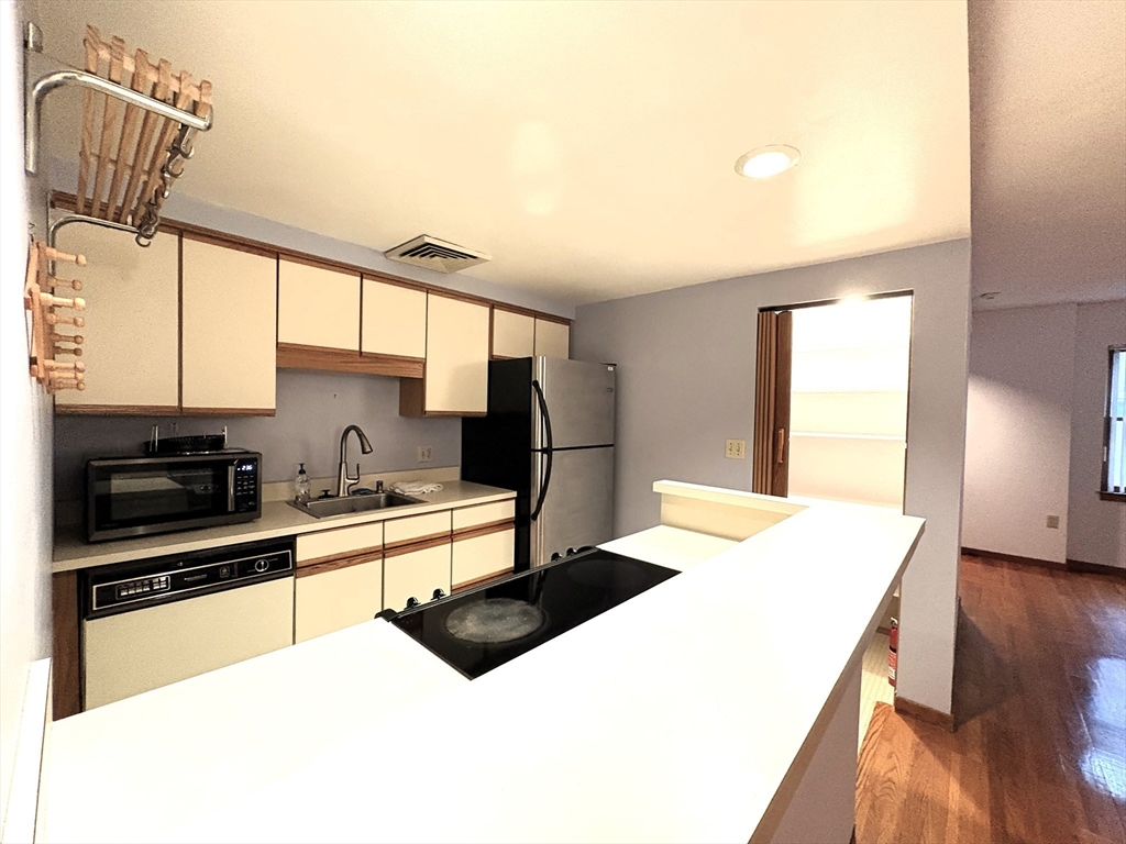 28 Parkman Street, Unit 2 Brookline, MA 02446 - Photo 4 of 11 a kitchen with stainless steel appliances kitchen island granite countertop a sink a stove a microwave a counter top space and cabinets