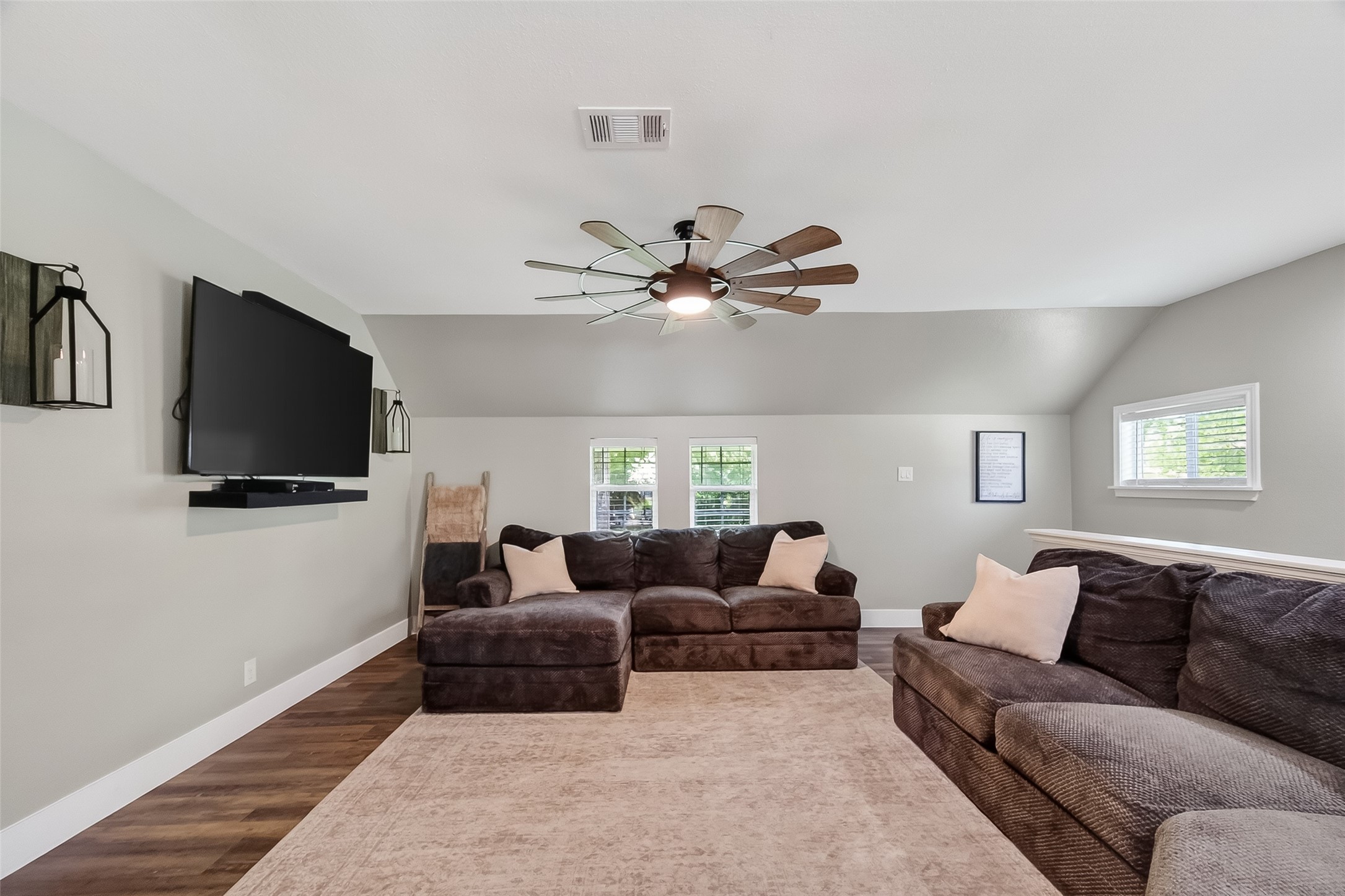819 Sentinel Oaks Pinehurst, TX 77362 - Photo 12 of 38 This inviting living room features neutral walls, a large sectional sofa, and a mounted flat-screen TV. A modern ceiling fan and soft lighting create a cozy atmosphere, while two small windows offer natural light. The space is perfect for relaxation and entertainment.