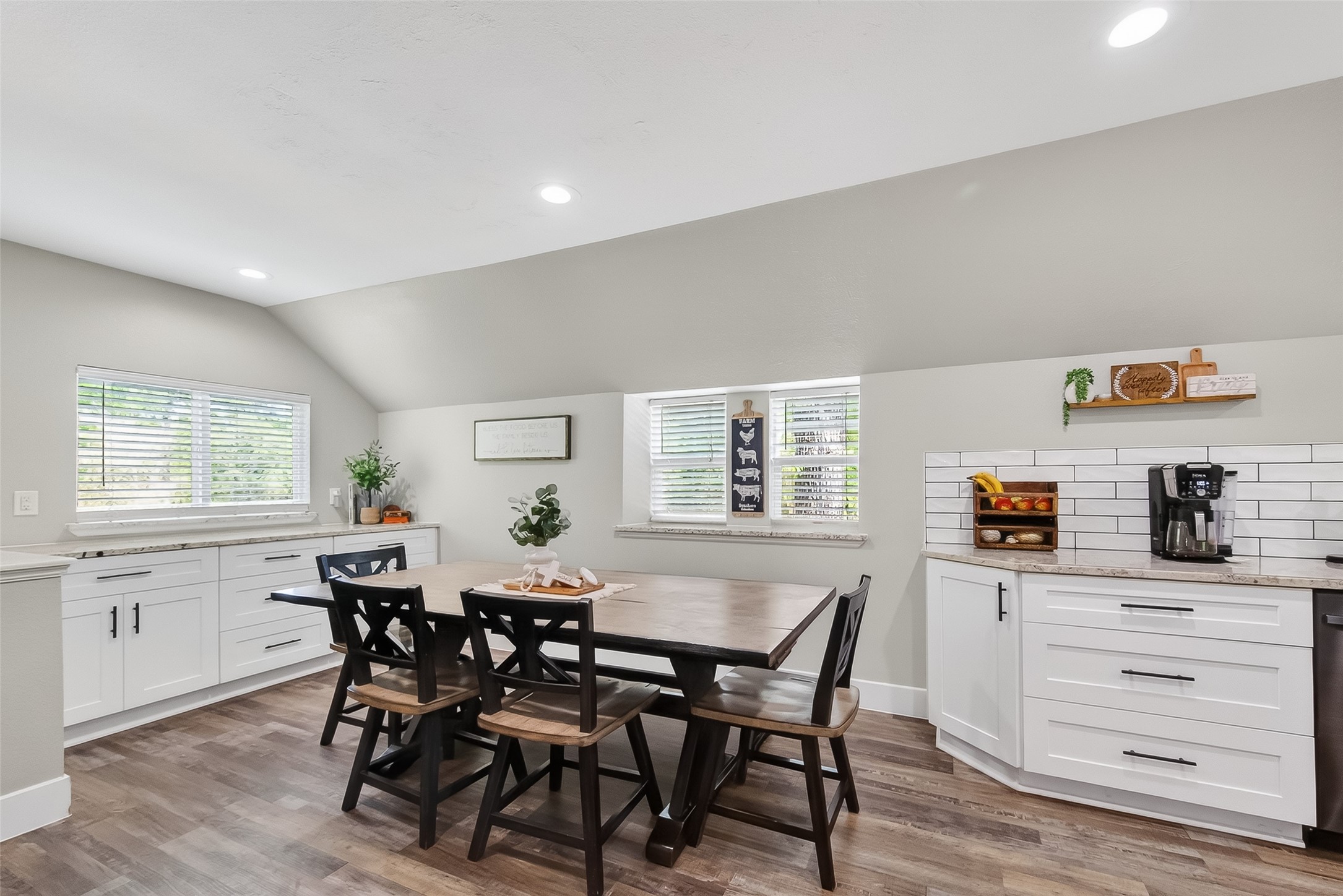 819 Sentinel Oaks Pinehurst, TX 77362 - Photo 13 of 38 Bright, modern kitchen with white cabinetry, wood flooring, and a cozy dining area. Features a large table, ample natural light, and stylish decor.
