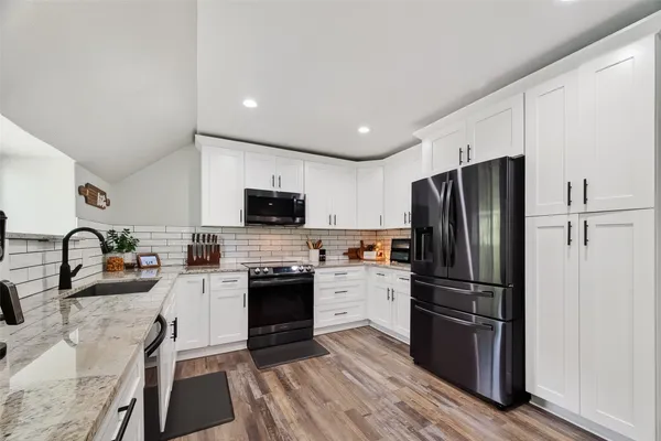 a kitchen with stainless steel appliances kitchen island granite countertop a refrigerator a stove a sink a dining table and chairs with wooden floor