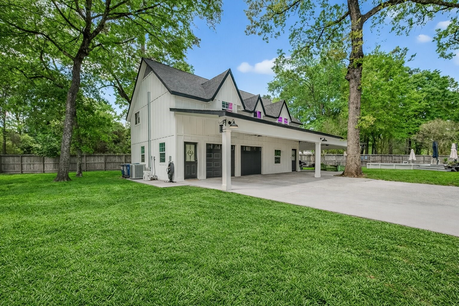 819 Sentinel Oaks Pinehurst, TX 77362 - Photo 2 of 38 Charming two-story home with a modern farmhouse design, featuring a spacious carport and lush green lawn. Surrounded by mature trees, it offers a serene and private setting.