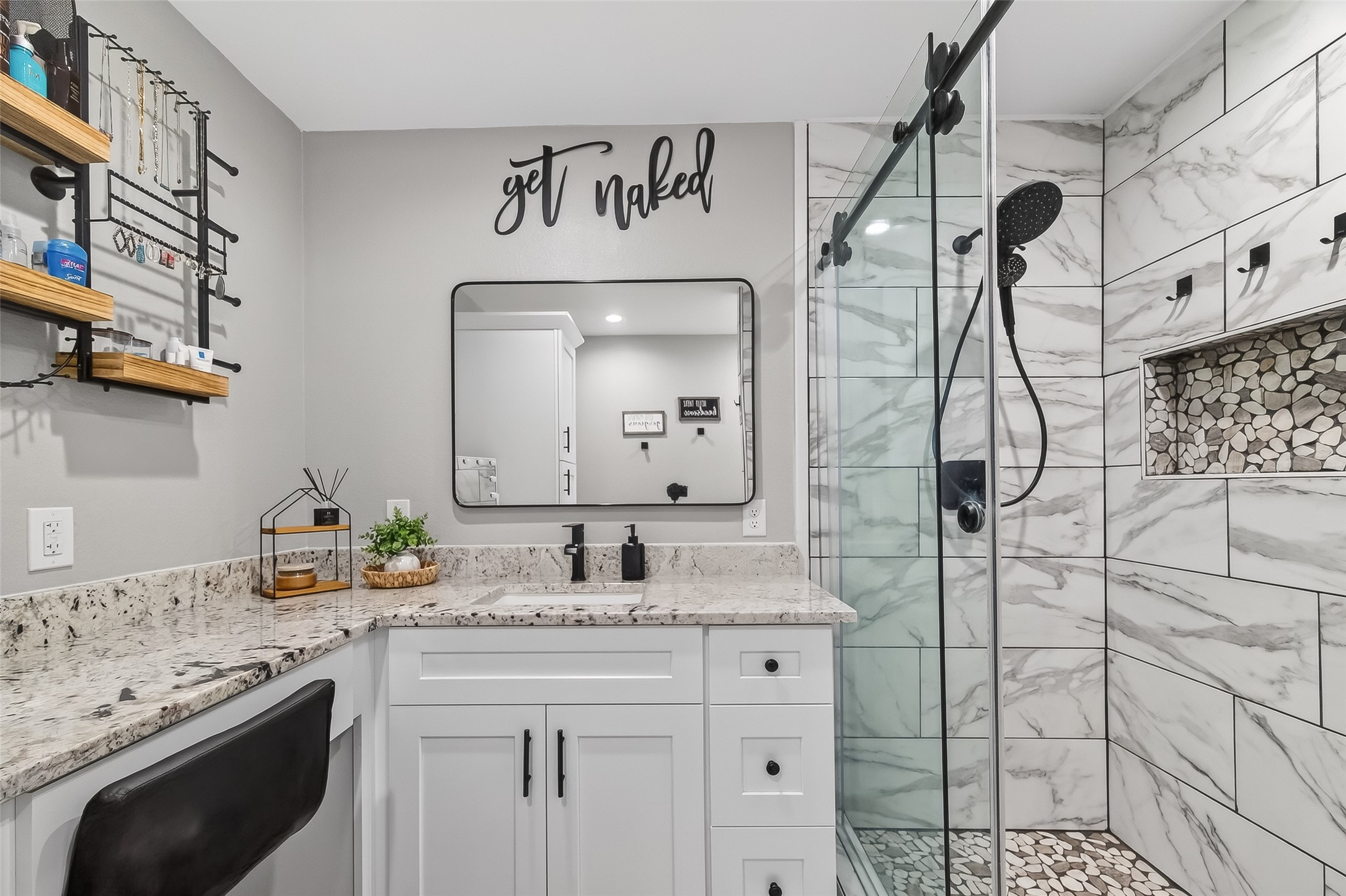 819 Sentinel Oaks Pinehurst, TX 77362 - Photo 24 of 38 This modern bathroom features a sleek design with marble-patterned tiles, a glass-enclosed shower with pebble flooring, and a stylish vanity with granite countertops. Cozy wall decor adds a touch of personality.