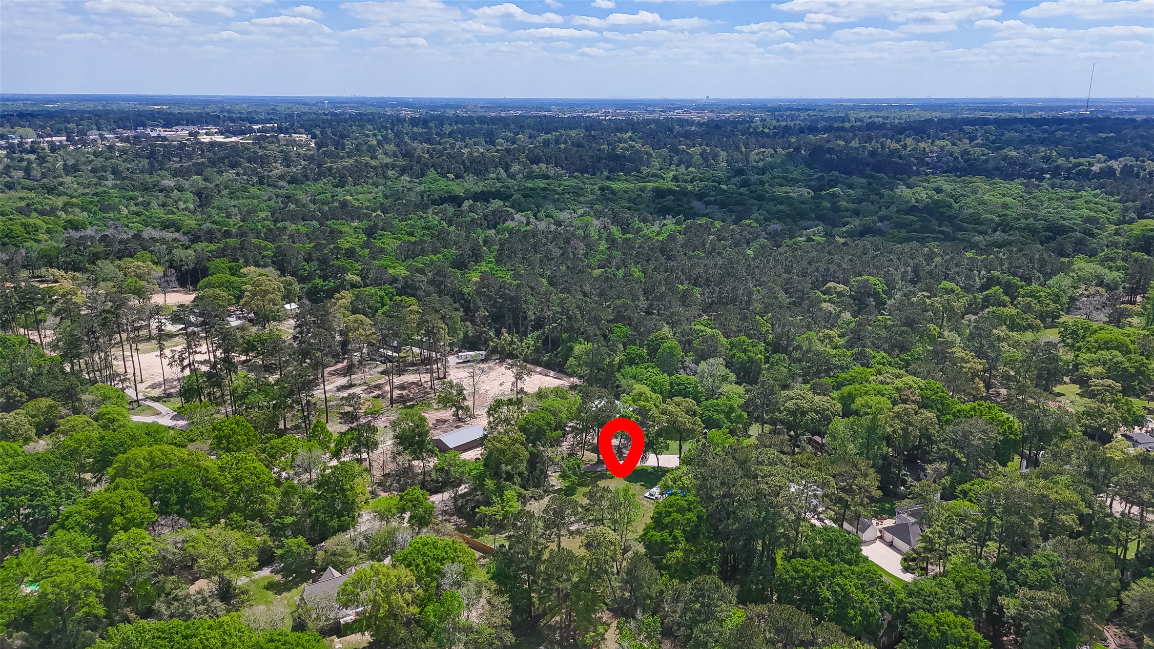 819 Sentinel Oaks Pinehurst, TX 77362 - Photo 38 of 38 This aerial photo showcases a property surrounded by lush greenery and dense forest, offering privacy and a serene environment. The red marker highlights the location of the home, which is nestled among trees, providing a natural and tranquil setting.